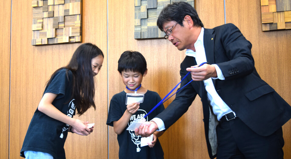 President Chikanami giving “Employee IDs” to children